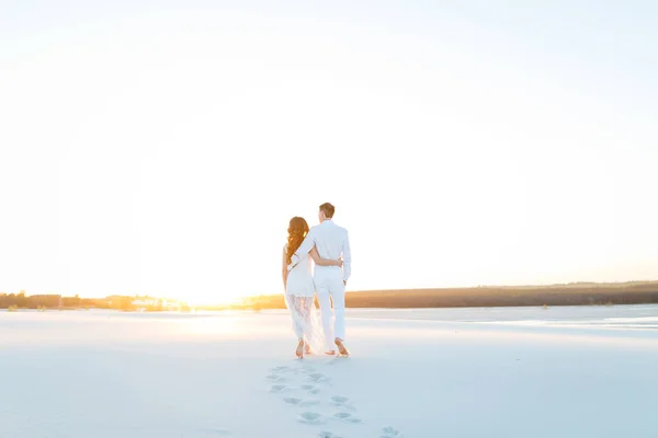 Recém-casados caminham descalços na areia do deserto branco — Fotografia de Stock