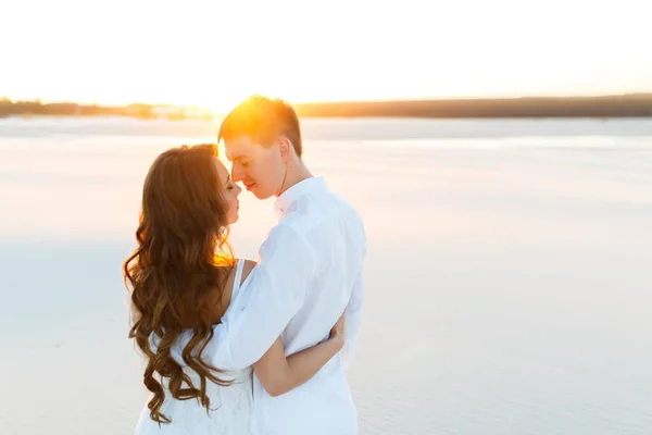 Brudgummen kramar bruden i öknen vid solnedgången — Stockfoto
