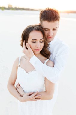 Romantik bir balayı gezisi sırasında beyaz bir çölde sarılan genç çift..