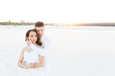 Romantik bir balayı gezisi sırasında beyaz bir çölde sarılan genç çift..