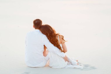 Romantik bir balayı gezisi sırasında beyaz bir çölde sarılan genç çift..