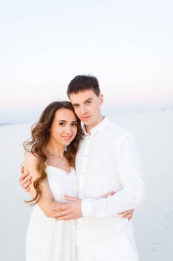 Romantik bir balayı gezisi sırasında beyaz bir çölde sarılan genç çift..