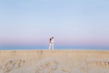 Romantik bir balayı gezisi sırasında beyaz bir çölde sarılan genç çift..