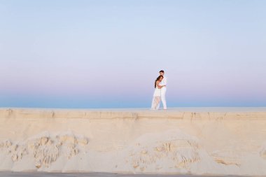 Romantik bir balayı gezisi sırasında beyaz bir çölde sarılan genç çift..