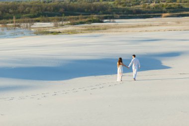 Aşıklar beyaz çölde kumda yalın ayak yürür. Çölde aşk, yeni evliler..