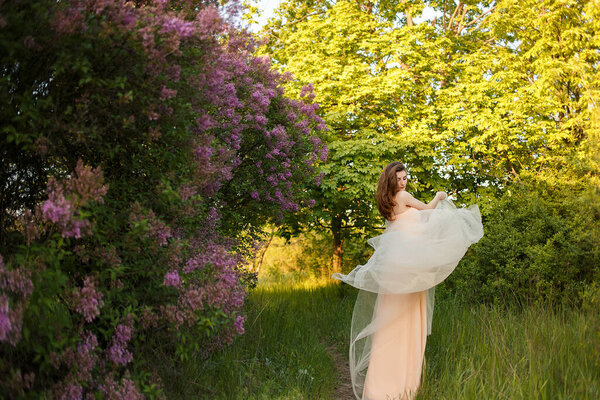 Beautiful fine art bride with a veil in a lilac garden