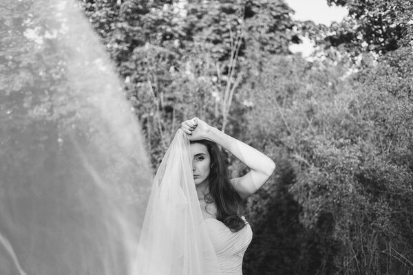 Fine Art Portrait of a beautiful bride with a veil in a summer garden