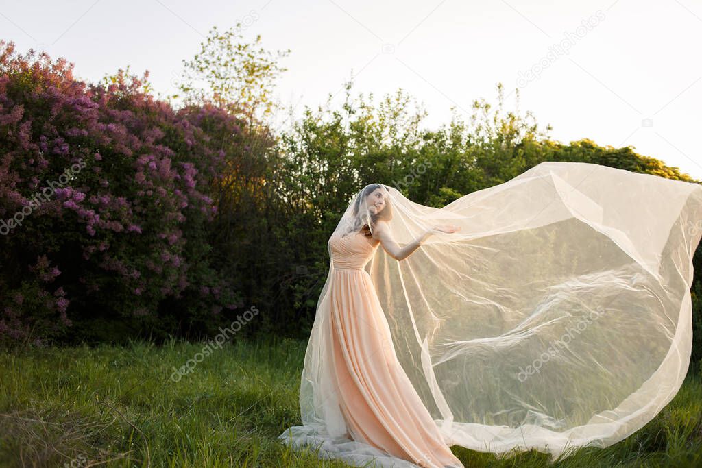 Beautiful fine art bride in a veil in a lilac garden