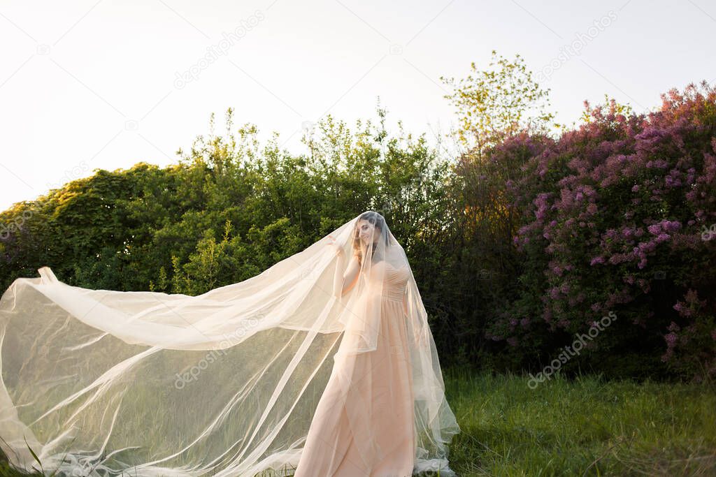 Fine art portrait of a bride in a long veil in nature