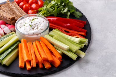 Sağlıklı sebzeler yoğurt soslu kayrak taşı yuvarlak tahtada, üst manzara kapalı, boşluk kopyala