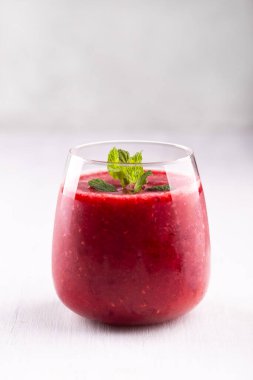 Beyaz taş masada bir bardak çilekli ve ahudududulu smoothie, sağlıklı kahvaltı içeceği.