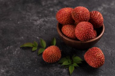Tahta bir kasede, arka planda, fotokopi alanı olan olgun, sağlıklı bir liçi meyvesi.