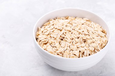 Eski moda yulaflar gri taş masada beyaz bir kasede yuvarlanır.