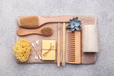 Doğal taştan arka planda yeniden kullanılabilir banyo malzemeleri, ahşap tarak, diş fırçası, deniz süngeri, kulak çubuğu, katı sabun, shea veya hindistan cevizi yağı.