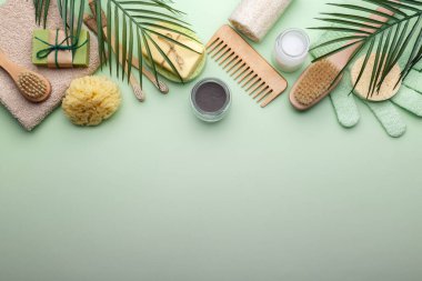 Sıfır atık yeniden kullanılabilir banyo öğeleri yeşil arka planda, ahşap tarak, diş fırçası, deniz süngeri, kulak çubuğu, katı sabun, shea veya hindistan cevizi yağı, düz kopya alanı