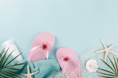 Mavi arka planda plaj aksesuarları, güneş gözlüğü, güneş kremi, parmak arası terlik, havlu ve şapka, yaz tatili konsepti, fotokopi alanı