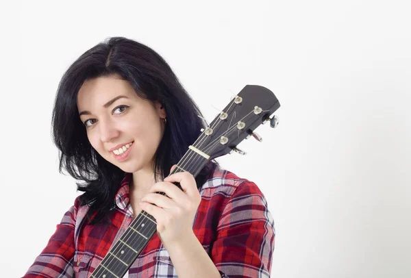 Kareli gömlekli bir akustik gitar tutan genç sevimli kız
