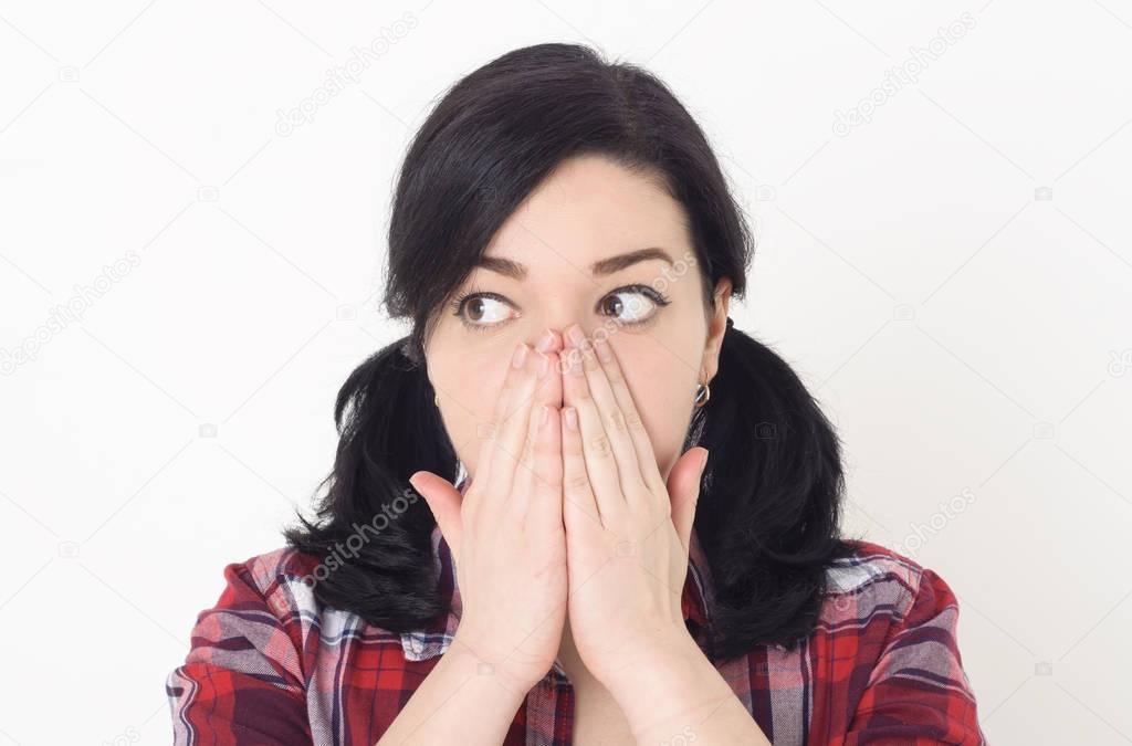 Young teenage girl severely shocked by something or someone and very surprised looking to the side, her hands covers mouth and eyes opened wide