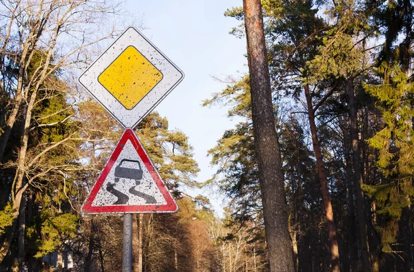 Dirty traffic sign Slippery road in the forest, careful driving in the countryside travel. — Stock Photo, Image