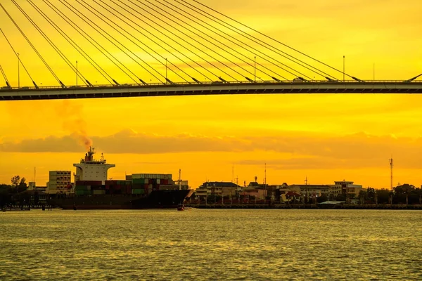 Container lading Oceaan schip drijven op de rivier en passeren onder brug — Stockfoto