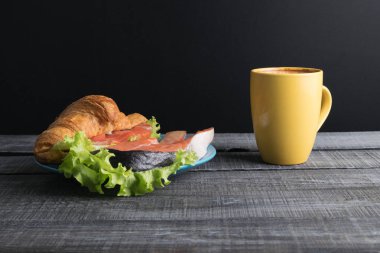 Kruvasan somon ve marul gri ahşap zemin üzerine