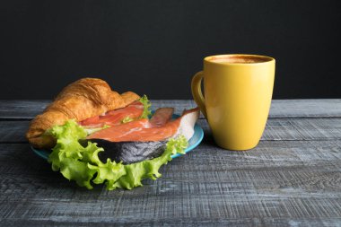 Kruvasan somon ve marul gri ahşap zemin üzerine