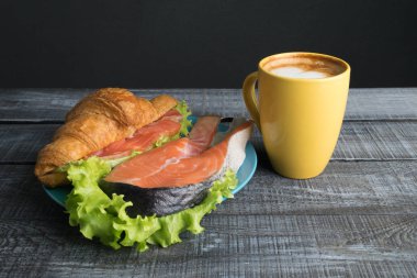 Kruvasan somon ve marul gri ahşap zemin üzerine