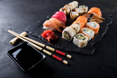 Yılan balığı, somon ve ton balığı suşi yemek çubukları, koyu arka plan ile