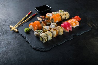 Yılan balığı, somon ve ton balığı suşi yemek çubukları, koyu arka plan ile