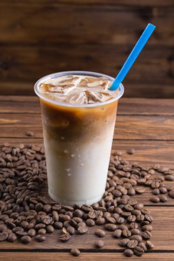 Buzlu kahve paket servisi olan restoran Kupası ve ahşap zemin üzerine kahve çekirdekleri