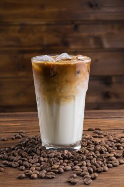 Buzlu kahve cam ve ahşap zemin üzerine kahve çekirdekleri