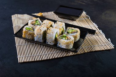 Uramaki suşi bambu peçete üzerinde siyah plaka üzerinde 