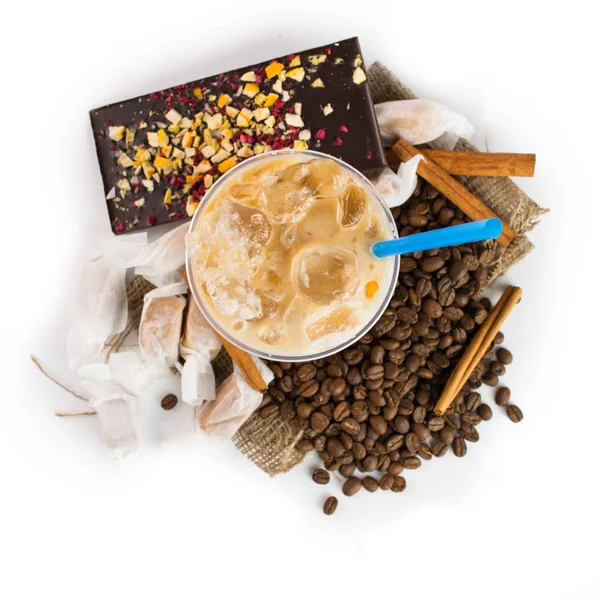Ice coffee in takeaway cup, chocolate bar and coffee beans on wooden background