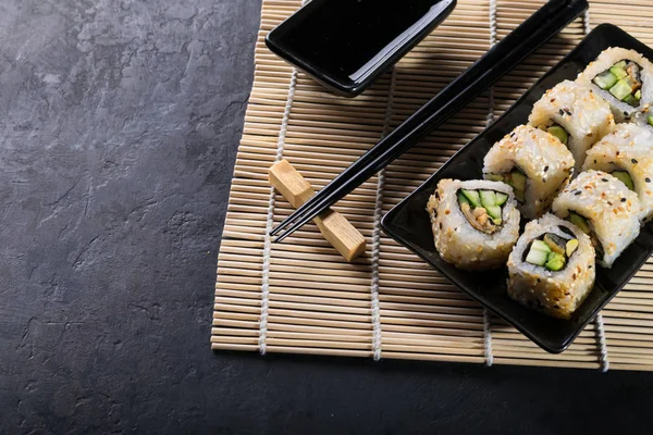 Uramaki sushi on black plate on bamboo napkin