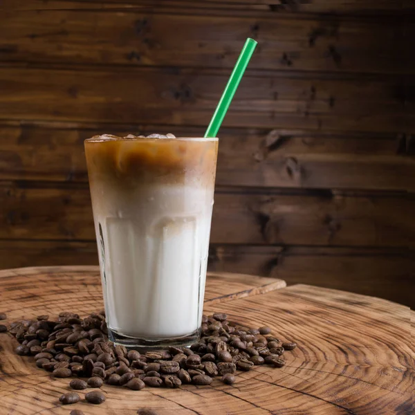 Iskaffe i glas och kaffebönor på trä bakgrund — Stockfoto