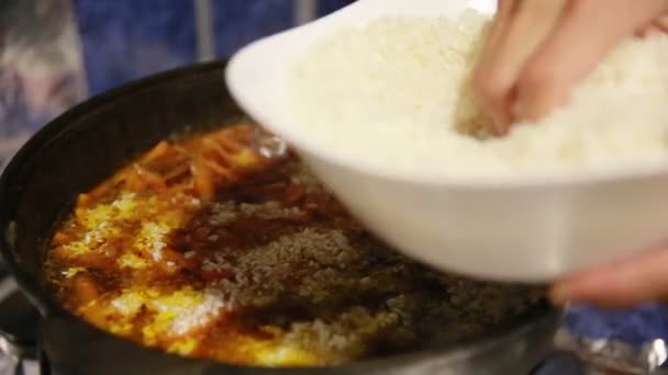 Cocinar pilaf, shef añade arroz blanco en la tetera de hierro fundido — Vídeo de stock