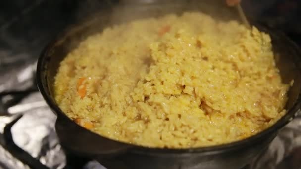 Kochen pilaf, shef rührt sanft die oberste Schicht des pilaf in gusseisernen Wasserkocher — Stockvideo