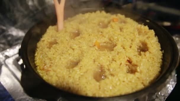 Cocinar pilaf, shef hace agujeros para la ebullición de la pilaf en hervidor de hierro fundido — Vídeo de stock