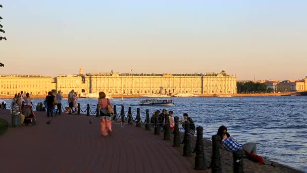 La gente camina a lo largo del muelle cerca de la fortaleza de Pedro y Pablo. Vista al palacio de invierno — Vídeos de Stock