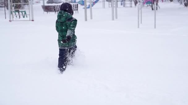 Όμορφη χαρούμενη preschooler αγόρι τρέχει μακριά μέσω πολύ βαθύ χιόνι. — Αρχείο Βίντεο