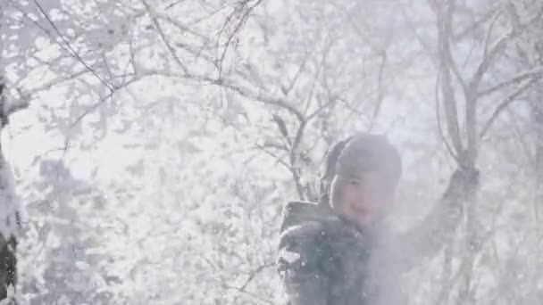 Alegre niño encantador sacude una rama cubierta de nieve, cámara lenta — Vídeos de Stock