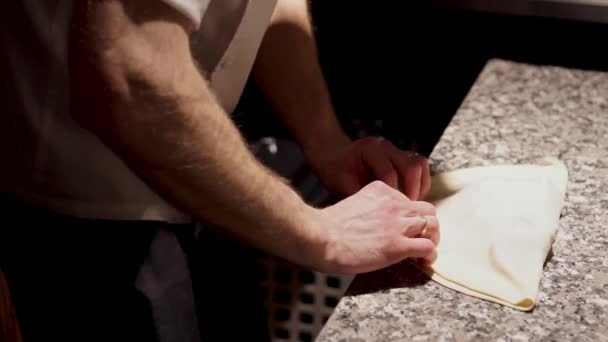 Шеф-повар запечатывает закрытую пиццу и кладет ее в духовку с помощью кулинарной лопаты — стоковое видео