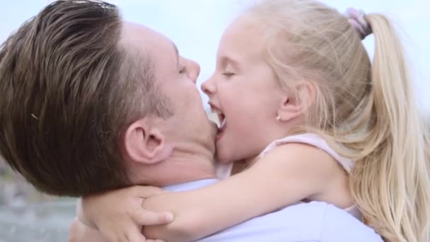 Medelålders far omfamnar sin dotter. Ljushårig liten flicka ler glatt — Stockvideo