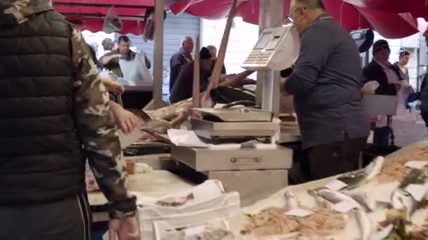 Seller in a red apron cuts swordfish, cleans insides. Old fish market in Catania — Stock Video