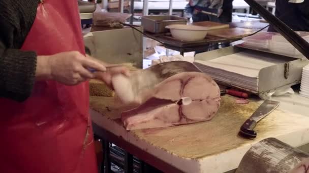 Verkoper in een rood schort snijdt zwaardvis, reinigt binnenkant. Oude vismarkt in Catania — Stockvideo