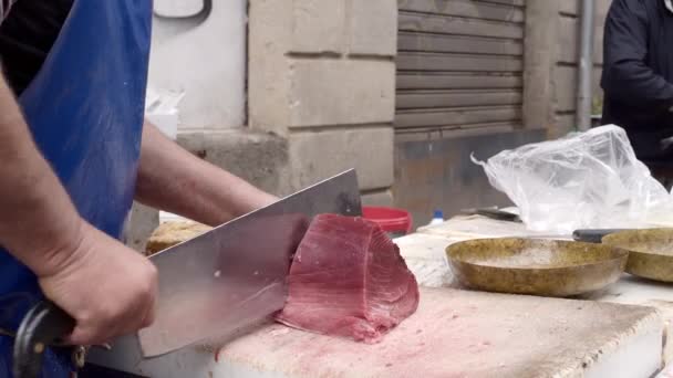Obchodník krájí maso z tuňáka na tenké plátky se sekáčkem na kamenné desce — Stock video