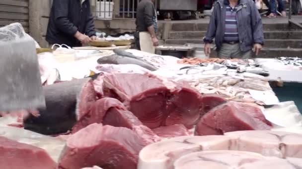 Купец режет тунец тонкими ломтиками с тесаком на каменной доске — стоковое видео