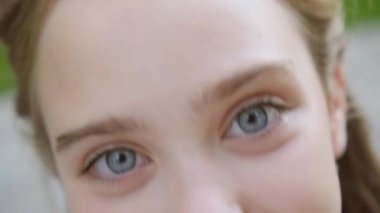 Uzun saçlı mavi gözlü sarışın kameraya bakar, arkasını döner ve geri döner.