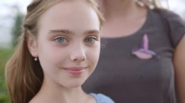 Anne küçük kızına doğru eğilir, 10 yaşındaki kız gülümser, yakın plan.