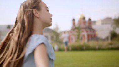 Hoş, uzun saçlı, mavi elbiseli kız yazın bir şehir parkında dans ediyor.